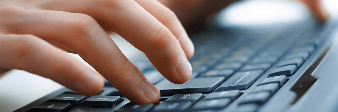 Detailaufnahme von Händen, die etwas auf einer Computer-Tastatur schreiben