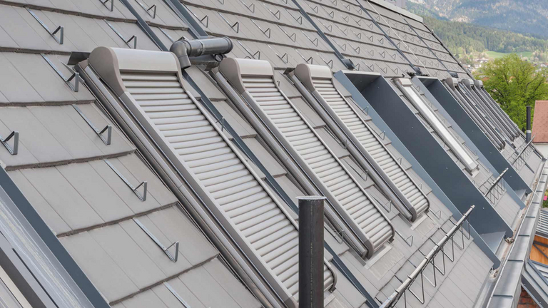 Eine Reihe von Dachfenstern mit heruntergefahrenen Außenrollladen