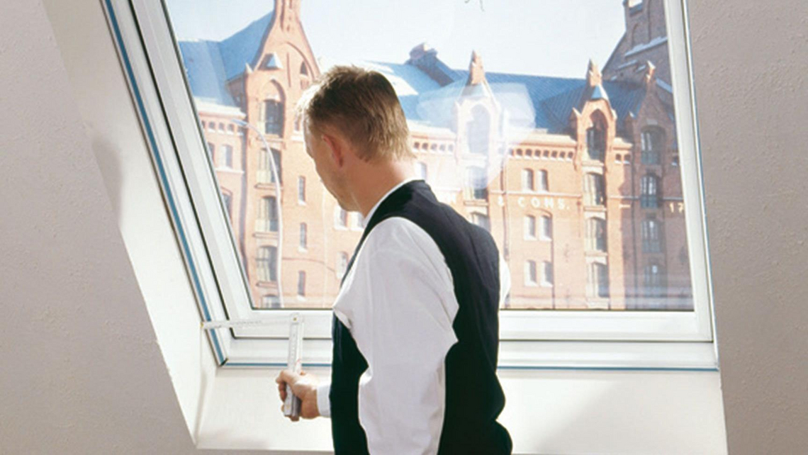 Ein Handwerker beim Ausmessen eines Dachfensters